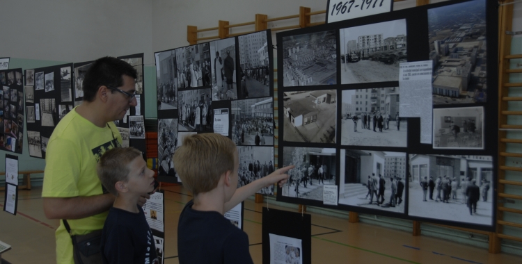 Un pare i dos nens miren les fotografies dels primers anys de l'escola. Foto: Ràdio Sabadell
